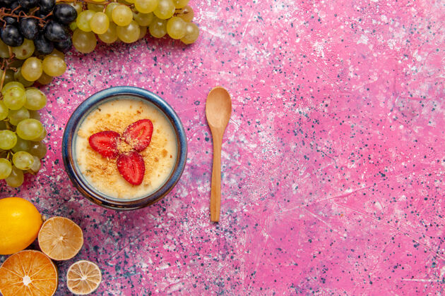 新鲜顶视图美味的奶油甜点与新鲜的绿色葡萄淡粉色背景甜点冰淇淋浆果奶油甜水果勺子背景顶部