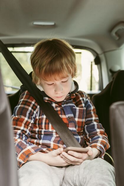 冒险孩子在车里玩智能手机 而在公路旅行汽车旅行孩子