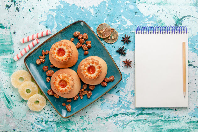 光俯视美味饼干与糖果和笔记本上的浅蓝色背景饼干饼干甜糖的颜色记事本顶部颜色