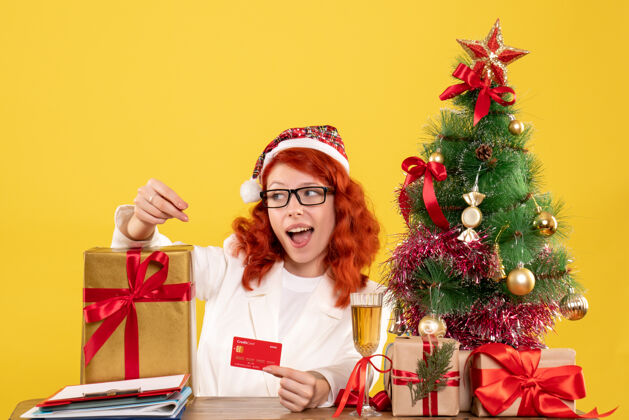圣诞节带礼物的女医生和浅黄色的银行卡美丽光人