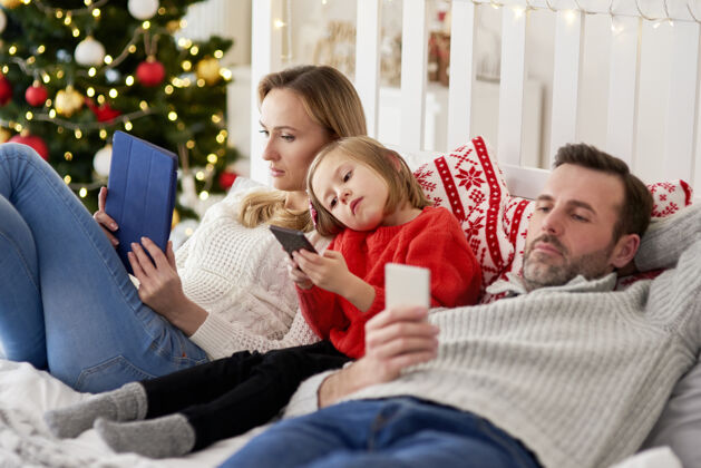 近距离无聊的一家人在床上用手机过圣诞节后代电话孩子