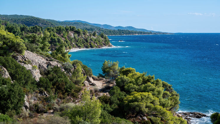 水希腊爱琴海沿岸 多岩石的小山上长满了树木和灌木 水面辽阔岩石天空南部