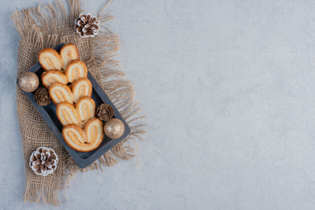 美味薄饼和圣诞装饰品放在大理石表面的小托盘上美味曲奇糖