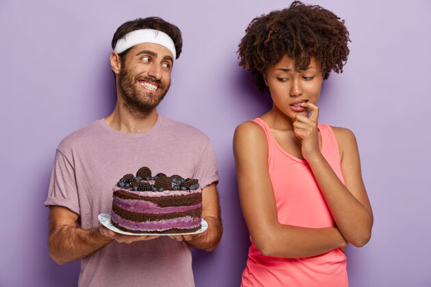 蛋糕一个非洲裔美国女人用手指捂住嘴 一边看着美味的蓝莓蛋糕一边感受诱惑一起饮食摆姿势