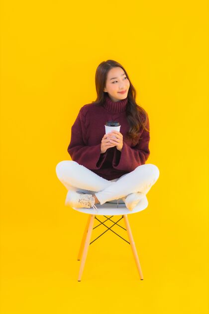 在线肖像美丽的亚洲年轻女子坐在黄色背景的椅子上休闲工作技术