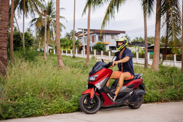运动在热带丛林的田野上纹着红色摩托车的壮运动旅游