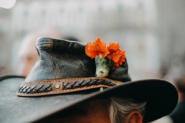 农场一个老人戴的一顶有桔黄色花的花式牛仔帽的特写镜头男性旧背景