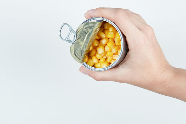 烹饪手拿一罐煮过的甜玉米手工黄色种子
