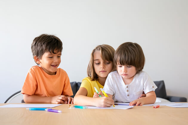 白种人快乐的孩子们在客厅里用记号笔画画可爱的小男孩和金发女孩坐在桌子旁 用笔在纸上画画 在家里玩耍童年 创造力和周末的概念生活年轻孩子