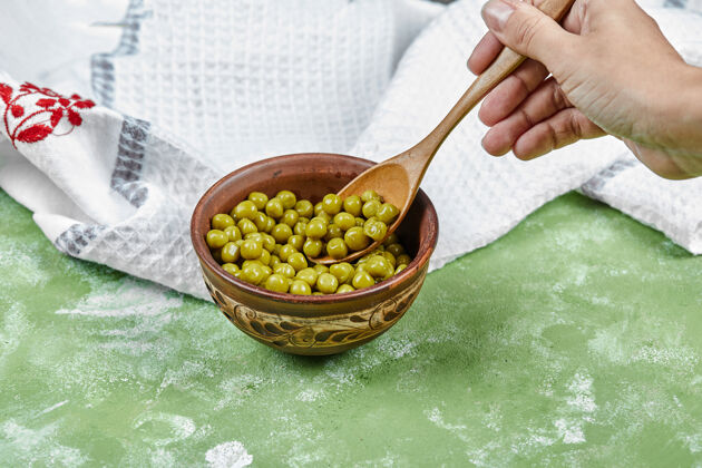 种子在一张绿色的桌子上手拿一勺煮青豌豆绿色天然罐装