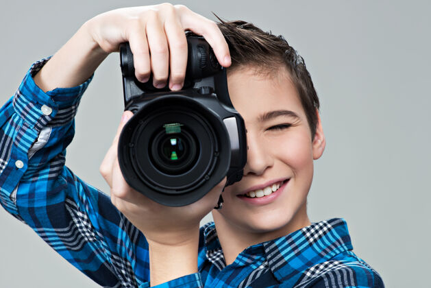 摄影拿着照相机的男孩在取景器里看男孩爱好相机