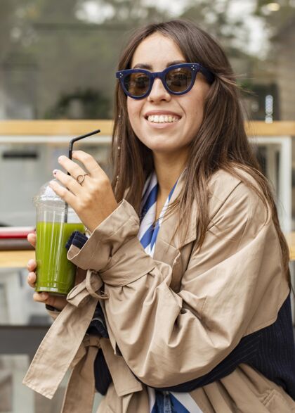 饮料中镜头的女人喝着绿色的冰沙果汁垂直食品