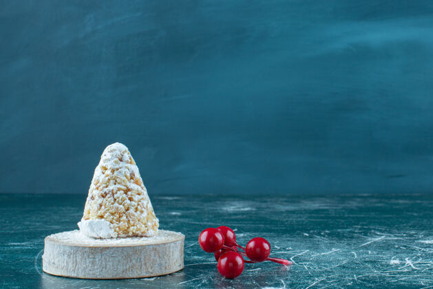 涂层一小束圣诞浆果 旁边是一个涂有香草的蛋糕 蓝色的浆果糕点糖