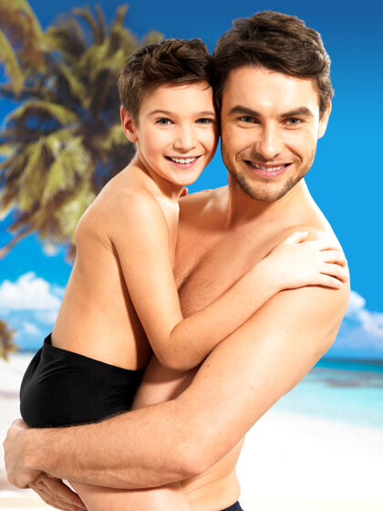 泳衣快乐微笑的父亲在热带海滩拥抱8岁的儿子的画像父母父亲后代