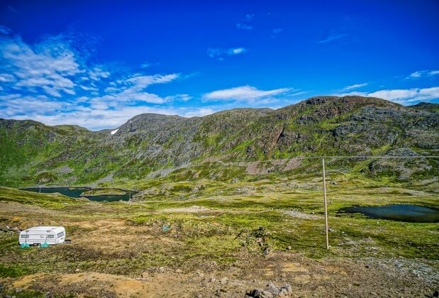 山在瑞典晴朗的蓝天下 可以看到青草覆盖的山脉和田野的美丽景色草地户外山