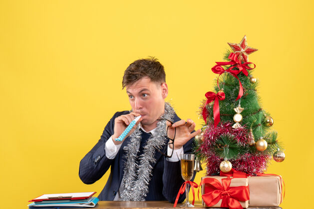 年轻人年轻人坐在圣诞树旁的桌子旁 用隔音器做圣诞礼物桌子艺人人