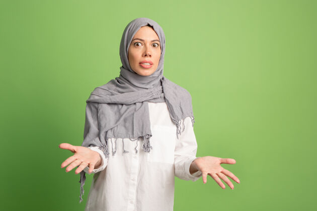 亚洲人争论 争论概念戴头巾的阿拉伯女人女孩肖像 在绿色工作室背景摆姿势年轻情绪化的女人人类情绪 面部表情概念正面视图伊斯兰分歧心烦意乱