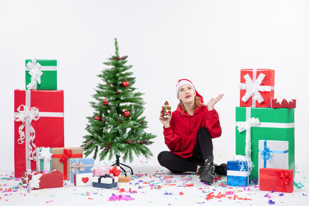 东西前视图：年轻女子围坐在白色墙壁上拿着礼物圣诞树节日十二月