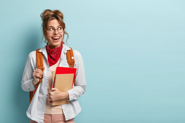 学生青春和返校理念微笑的女学生上额外的课 拿着笔记本 背着书包考试眼镜背包