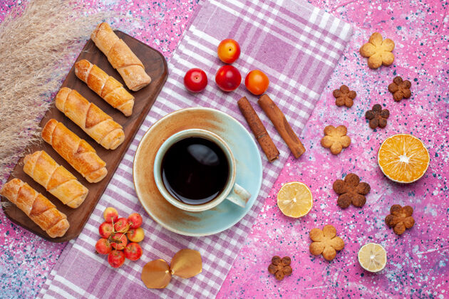 饼干在浅粉色的桌子上可以看到美味的小面包圈 还有一杯茶和饼干浅粉色糕点面团