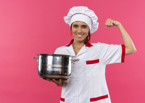 女微笑的年轻女厨师穿着厨师制服拿着平底锅 用复制空间展示出强烈的姿态拿着强壮厨师