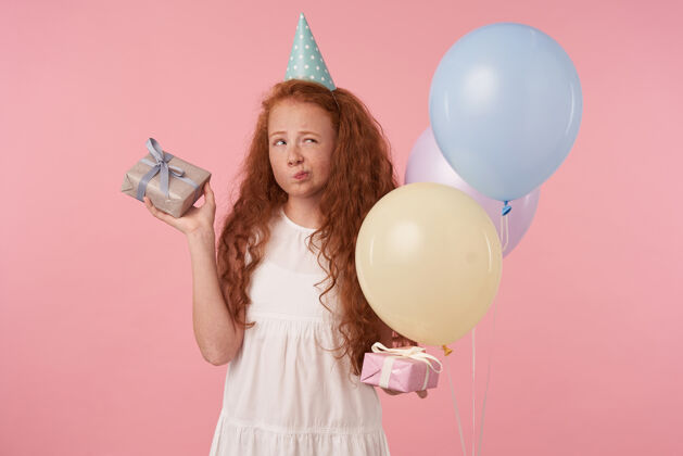 女学生身着节日服装的长发女孩儿肖像 手持礼品盒站在粉色背景上庆祝节日儿童和庆祝概念长礼物盒子