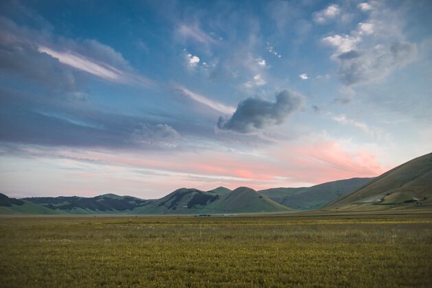 农业在意大利五彩缤纷的多云天空下 草地上美丽的绿色山脉的广角镜头乡村明亮天空