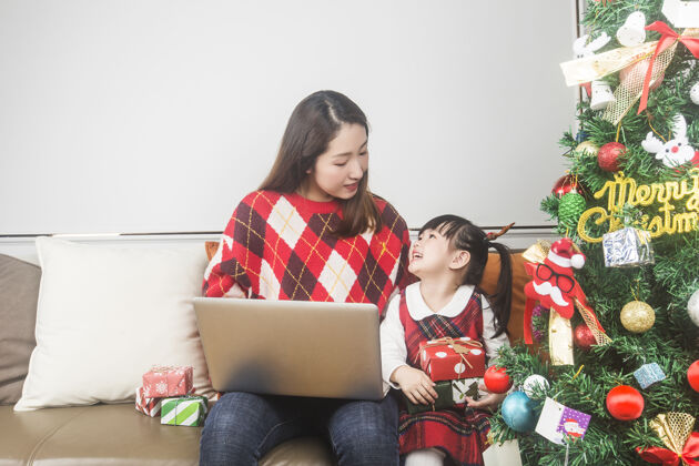 在一起快乐的妈妈和小女儿在家装饰圣诞树和礼物生活方式快乐人