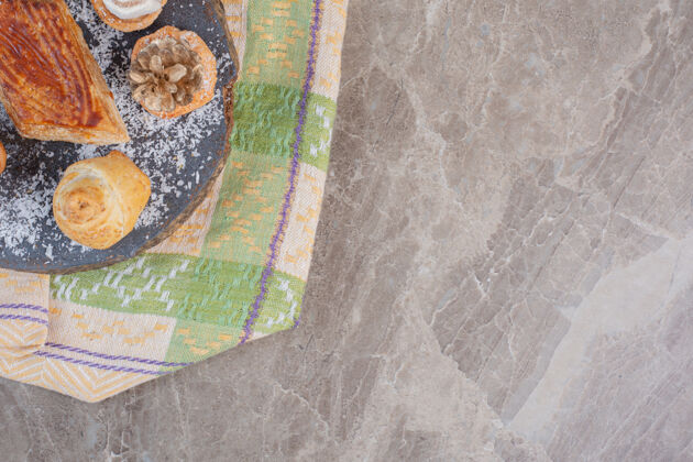 糕點美味的kyata周圍有餅干 上面放著木棉花和松果 放在大理石板上桌布美味板
