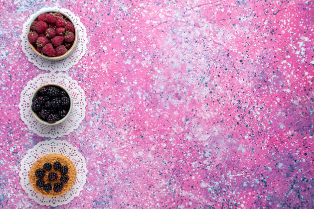 甜小黑莓蛋糕的顶视图 浅粉色表面上有覆盆子和新鲜黑莓生的蛋糕覆盆子