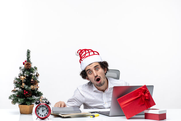笔记本电脑节日喜庆的心情与震惊的商人圣诞老人戴着帽子独自在白色背景的办公室里工作独自节日办公室