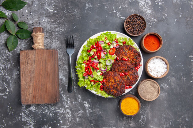 顶部俯视图美味的肉排与沙拉和调味品的灰色背景照片美食菜肉餐厅美味肉片蔬菜