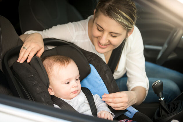 安全帶微笑的母親在車上的畫像 她的男嬰在安全座椅上男性坐著旅行