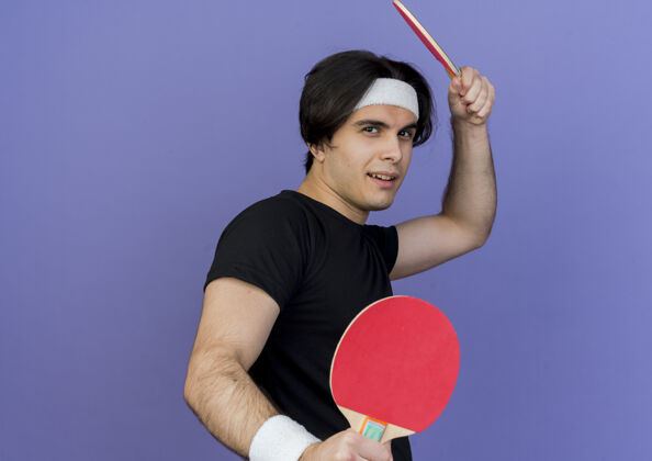 年轻穿着运动服 头戴头巾 手拿球拍打乒乓球的年轻人 表情严肃严肃抱着站着