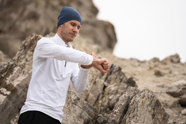 健康大自然中的年轻人在岩石附近看手表运动跑步锻炼