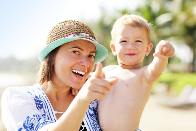 手指妈妈和她的小儿子在沙滩上玩得很开心男孩健康人