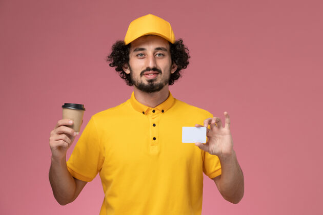 名片正面图：身穿黄色制服 披风的男性快递员手持咖啡杯和粉色墙上的卡片帽子持有杯子