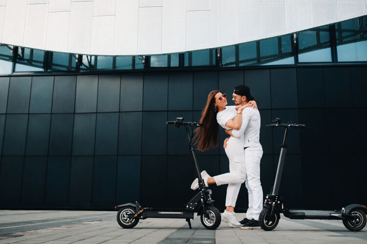 爱一个女孩和一个男孩骑着电动滑板车在城市里走来走去 一对恋人骑着滑板车夫妻关系踢摩托车