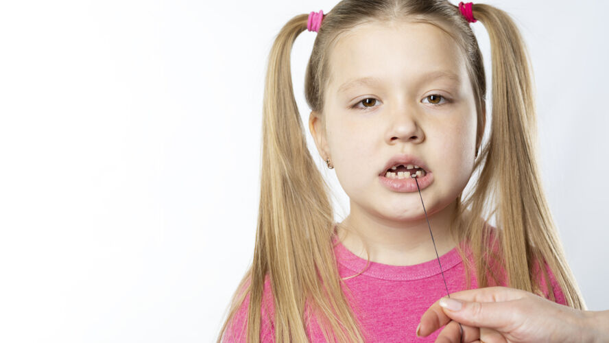 牙齿一个穿粉红色衣服的小女孩拿着乳牙上的线人跌倒小