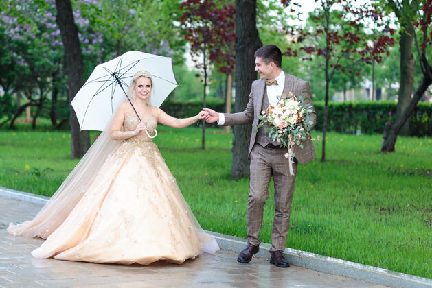 新娘和新郎快乐的新郎新娘打着白色雨伞 在夏天的公园里露天婚礼家庭女人雨伞