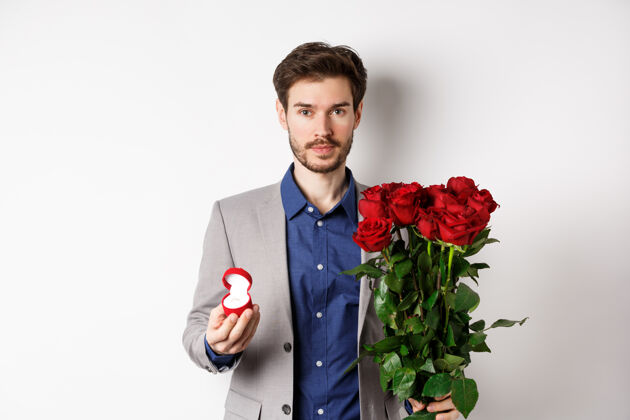 玫瑰帅哥西装革履准备求婚 站在红玫瑰和订婚礼盒里 制造浪漫惊喜 白色背景感情同性恋浪漫