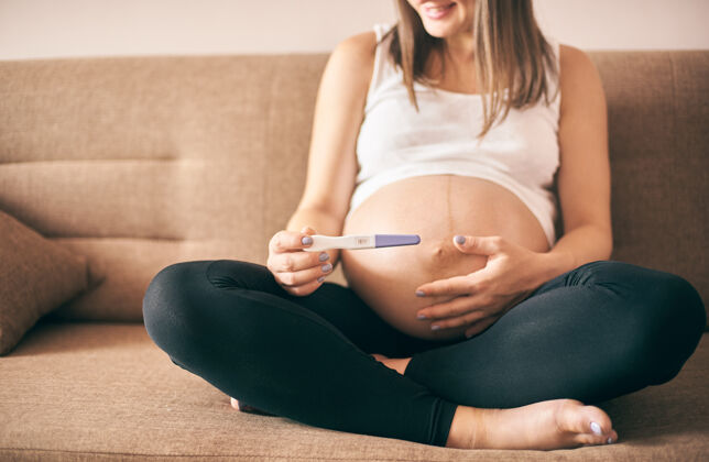 生活方式年轻女子手中的怀孕测试特写胎儿室内显示