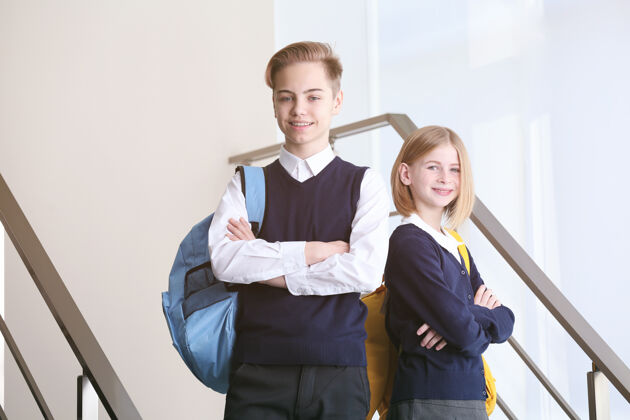 站穿着校服的可爱男孩和女孩站在楼梯上铁路姿势一起