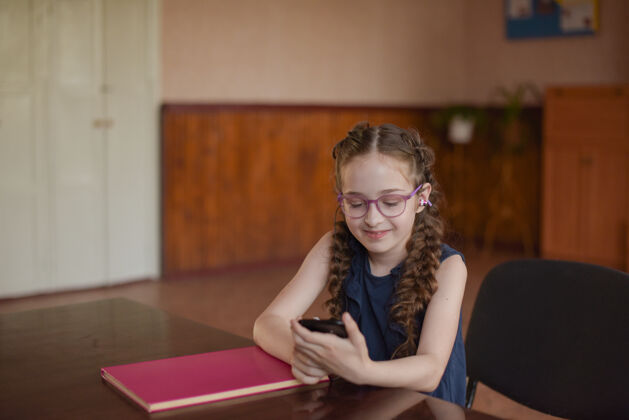 可爱教室里坐在桌子旁拿着课本的女学生一个穿着蓝色裙子扎着辫子的女孩桌子小学生书房