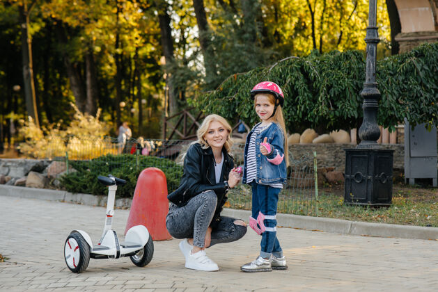 生态一位母亲教她的小女儿在日落时在公园里骑赛格威公共爱电力