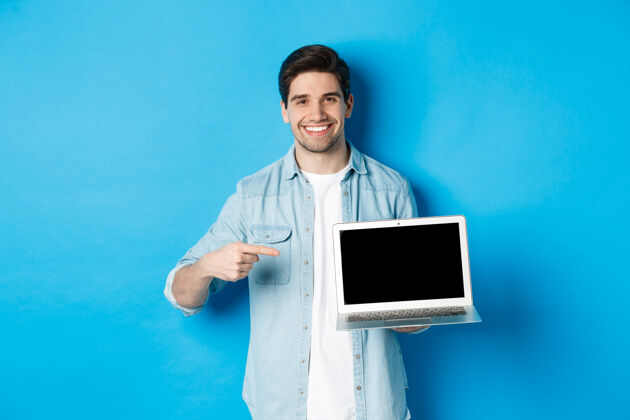快乐英俊的年轻人用手指着电脑屏幕朋友宣传自信
