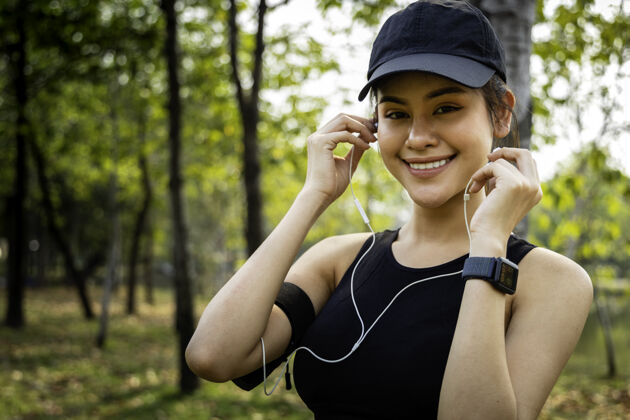 训练特写一位在户外穿着运动服和耳机的亚洲女跑步者女性在公园锻炼时休息耳机健康休息