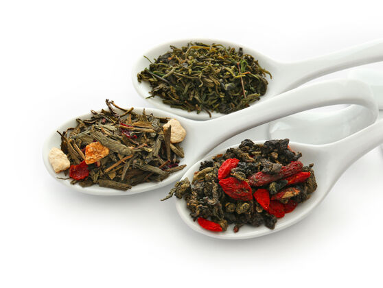 叶不同种类的干茶放在陶瓷汤匙里 隔离在白色上混合印度分类