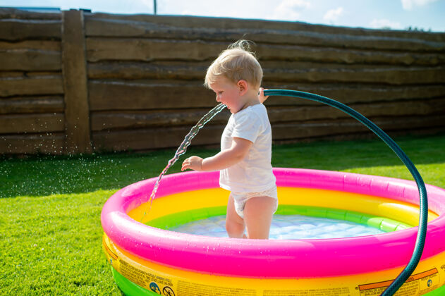 可爱一个有趣的小男孩在儿童游泳池里取水男孩情感爱