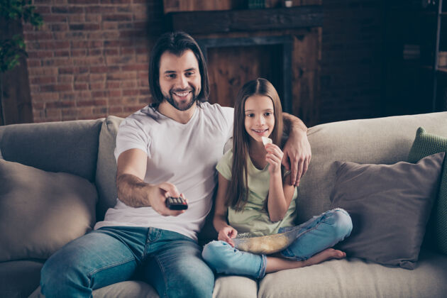 电影美丽可爱的小女孩和英俊年轻的爸爸坐在舒适的沙发上的照片一天在一起手表
